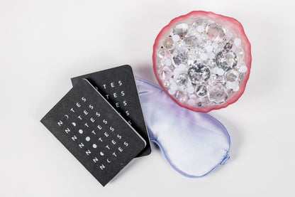 Black sleep mask with 'NITES' branding next to a pink eye mask with gemstones on a white background